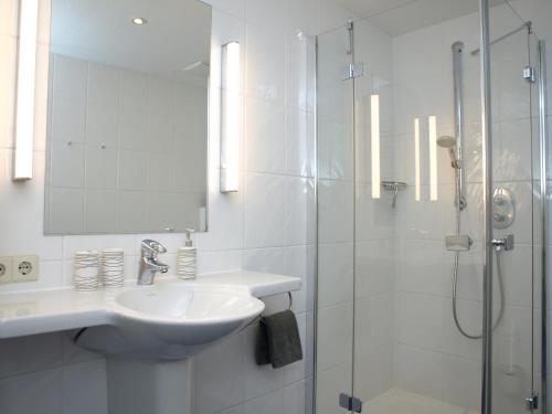 a white bathroom with a sink and a shower at Haus Sonnenhaken Wohnung 1 in Norderney
