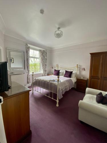 a bedroom with a bed and a tv and a couch at Kenilworth Guest House in Windermere