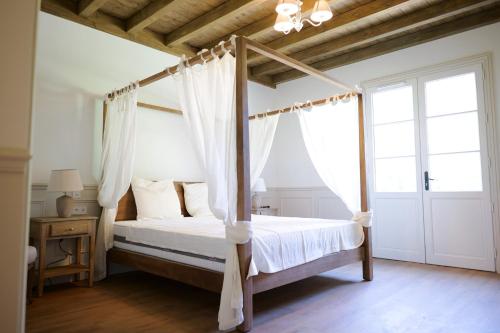 une chambre avec un lit à baldaquin avec des rideaux blancs dans l'établissement Château Le Moulin - Pomerol, à Pomerol