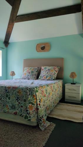 a bedroom with a bed with a floral bedspread and two lamps at Les Murmures de Charente in Villiers-le-Roux