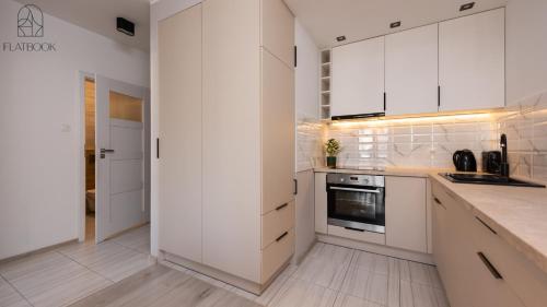 a white kitchen with white cabinets and appliances at Flatbook - City Center SPA Apartments 6B,C in Gdańsk