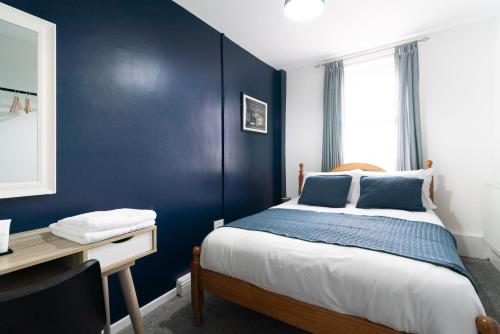 a bedroom with a blue wall with a bed and a desk at Citysteps Hotels Newcastle West in Newcastle upon Tyne