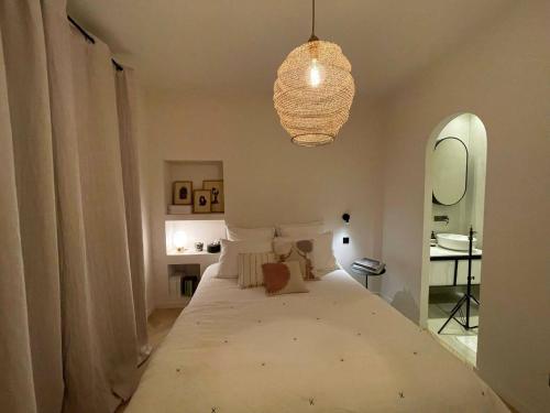 une chambre avec un grand lit blanc avec un lustre dans l'établissement Marais - Fancy one-bedroom decorated with taste, à Paris