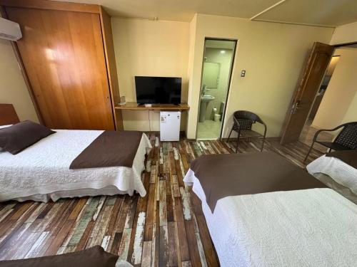 a hotel room with two beds and a flat screen tv at Hotel Cano in Iquique