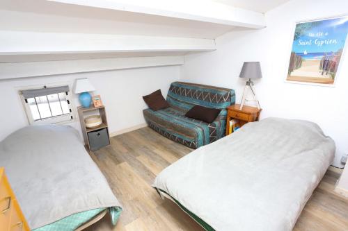 une chambre d'hôpital avec deux lits et un canapé dans l'établissement Maison fleurie quartier calme st Cyprien, à Saint-Cyprien