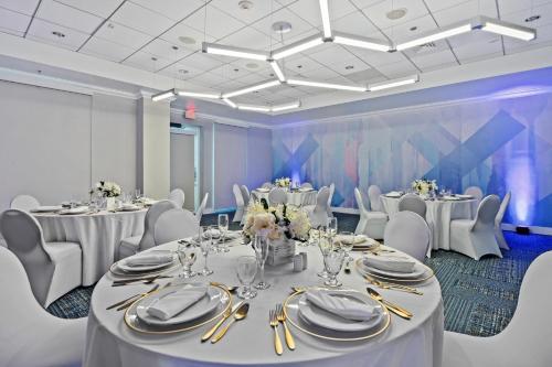 a banquet room with white tables and white chairs at Hilton Garden Inn Ft. Lauderdale Airport-Cruise Port in Dania Beach