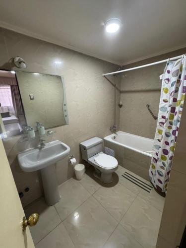 a bathroom with a sink and a toilet and a tub at Hotel Cano in Iquique
