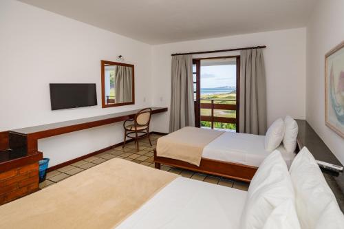 a hotel room with a bed and a television at Mirai Beach Hotel in Natal