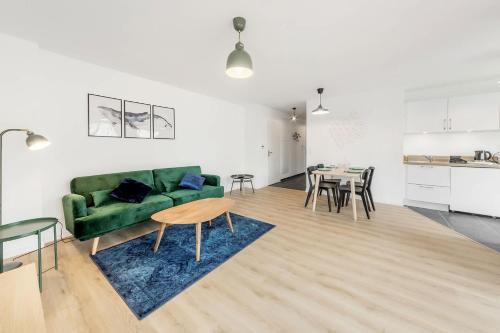 a living room with a green couch and a table at Bella Vista - Appartement 2 Chambres Moderne et Confortable in Saint-Coulomb