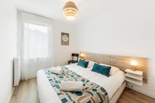 a white bedroom with a large bed with blue pillows at Bella Vista - Appartement 2 Chambres Moderne et Confortable in Saint-Coulomb
