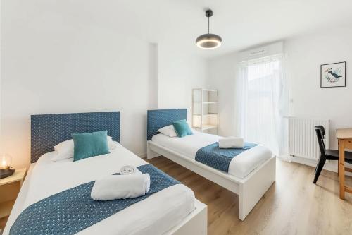 - une chambre avec 2 lits en bleu et blanc dans l'établissement Bella Vista - Appartement 2 Chambres Moderne et Confortable, à Saint-Coulomb