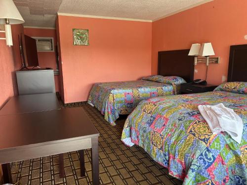 una habitación de hotel con dos camas y una mesa en Queen Elizabeth Motel, en Elizabeth City