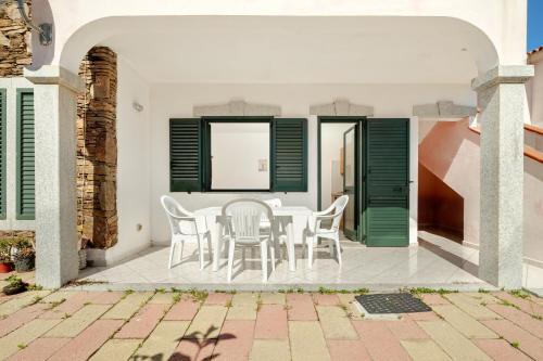 a patio with white chairs and green shutters at Limpiddu in Limpiddu