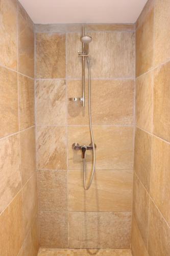 La salle de bains carrelée est pourvue d'une douche avec un tuyau. dans l'établissement Les Terrasses de la Roque-Alric, à La Roque-Alric