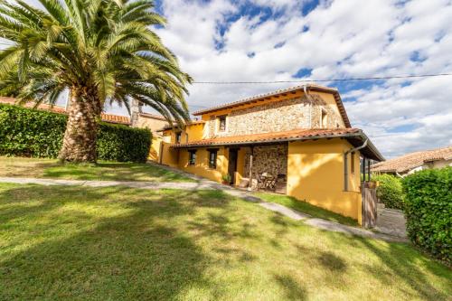 a house with a palm tree and a yard at La Casona del Cura 2, LIRIO in Pravia