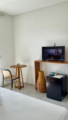 a room with a tv on a shelf with a table at Yahweh Hotel in São Miguel do Gostoso
