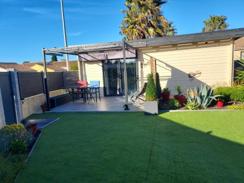 une arrière-cour avec de l'herbe verte et une terrasse. dans l'établissement chalet 2 personnes, à Marseillan