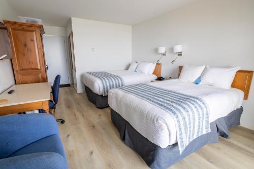 a hotel room with two beds and a blue couch at Pavillon sur Mer par Riôtel in Matane