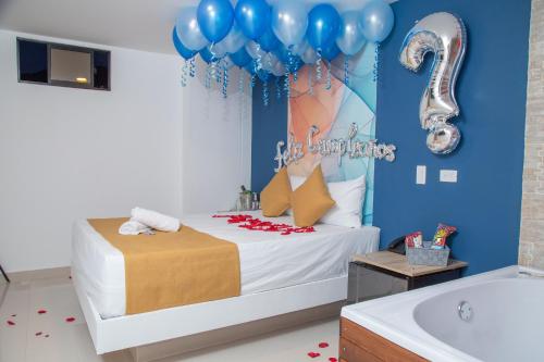 a room with a bed with balloons and a tub at Bajo la luna hotel in Medellín