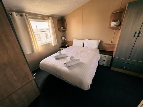 a small bedroom with a bed with towels on it at Beachside Caravan Retreat In Lowestoft Sleeps 6 in Lowestoft