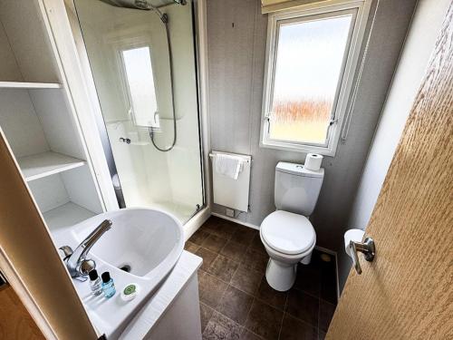a bathroom with a sink and a toilet and a window at Beachside Caravan Retreat In Lowestoft Sleeps 6 in Lowestoft