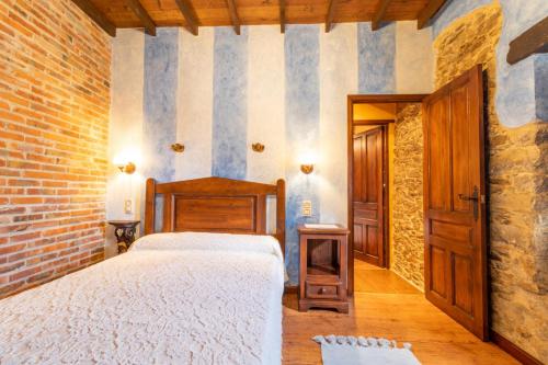 a bedroom with a bed and a brick wall at La Casona del Cura 3, CALÉNDULA in Pravia