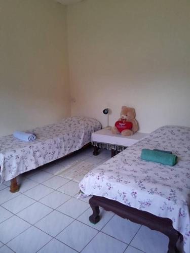a room with two beds and a teddy bear sitting on a table at Thongkham house in Ban Chek