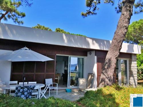 une maison avec une table et un parasol dans l'établissement Villa ACONIT - Les pieds dans l'eau, à Lecci