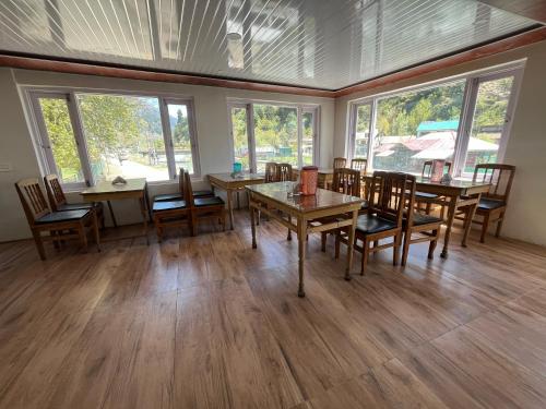 a dining room with tables and chairs and windows at The Sun Shine Pahalgam in Pahalgām