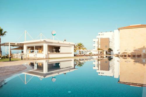 a building with its reflection in a body of water at Piere - Anne Beach Hotel in Ayia Napa