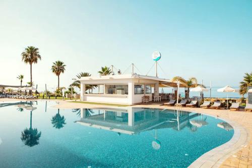 a swimming pool with blue water and palm trees at Piere - Anne Beach Hotel in Ayia Napa