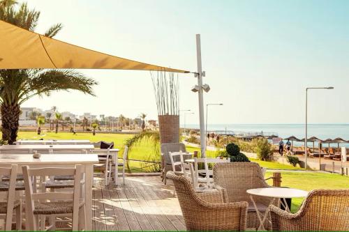 a patio with tables and chairs with the ocean in the background at Piere - Anne Beach Hotel in Ayia Napa