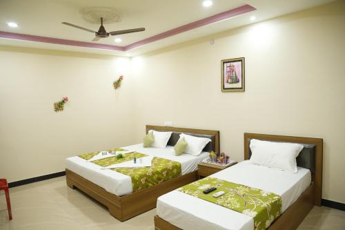a bedroom with two beds and a ceiling fan at Hotel New Amirtham inn in Palani