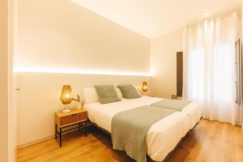 a bedroom with a bed and a table with a lamp at Bravissimo Ferreries Velles, with 2 bedrooms in Girona