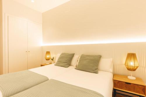 a white bedroom with two beds and two lamps at Bravissimo Ferreries Velles, with 2 bedrooms in Girona