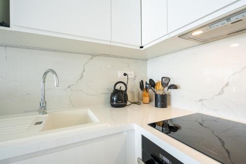 une cuisine blanche avec un évier et un comptoir dans l'établissement Ocean 90 face mer, à La Baule