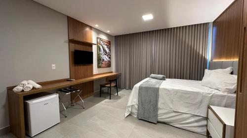 a bedroom with a bed and a desk with a television at Hotel Cachoeira in Cajazeiras