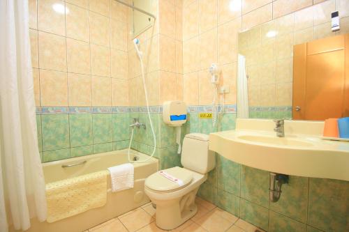 a bathroom with a toilet and a sink and a bath tub at East Commercial Affairs Hotel in Luodong
