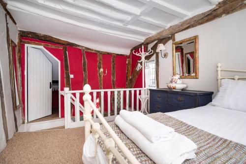 sypialnia z łóżkiem i czerwoną ścianą w obiekcie Hylton Cottage, Lavenham w mieście Lavenham