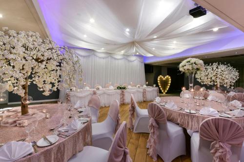 a banquet hall with white tables and chairs and flowers at Holiday Inn - Manchester - Oldham by IHG in Manchester