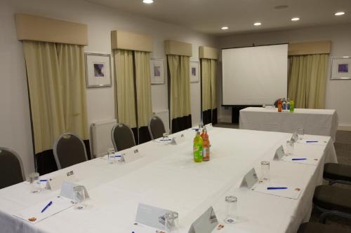 a meeting room with white tables and chairs and a screen at Holiday Inn - Manchester - Oldham by IHG in Manchester