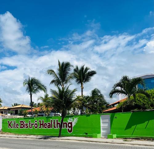 a green wall with palm trees in front of a street at Kite Bistro in Caucaia