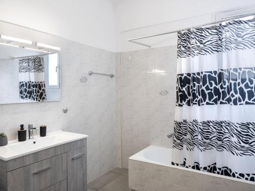 a bathroom with a black and white shower curtain at Sunrise By Athens Airport in Spáta