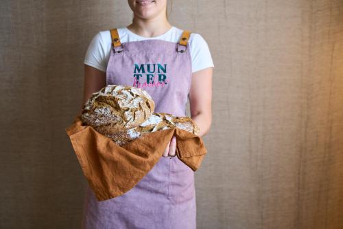 a woman in an apron holding a batch of bread at Henriette Stadthotel Vienna in Vienna