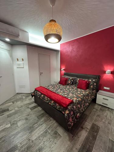 a bedroom with a bed with a red wall at Rosso Relativo in Acilia