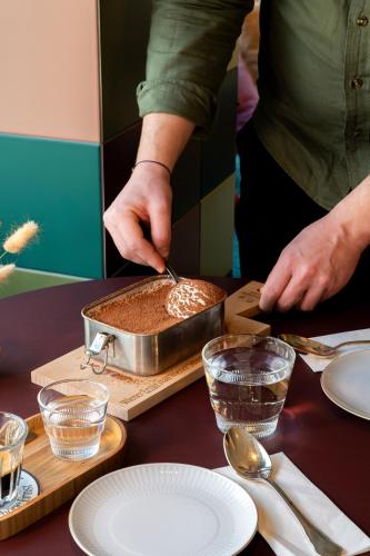 a person is preparing food in a pan on a table at Henriette Stadthotel Vienna in Vienna