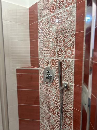 a shower with a glass door with a mosaic tile wall at Rosso Relativo in Acilia
