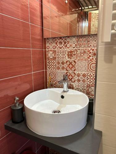 a white sink in a bathroom with red tiles at Rosso Relativo in Acilia