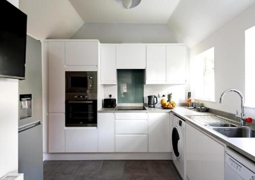 a white kitchen with white cabinets and a sink at Character House for Buisness, Holidays and Relocation in Frinton-on-Sea