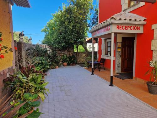 a red building with a red repetitionvention sign on a sidewalk at Hotel las Palmeras Suite in Celorio